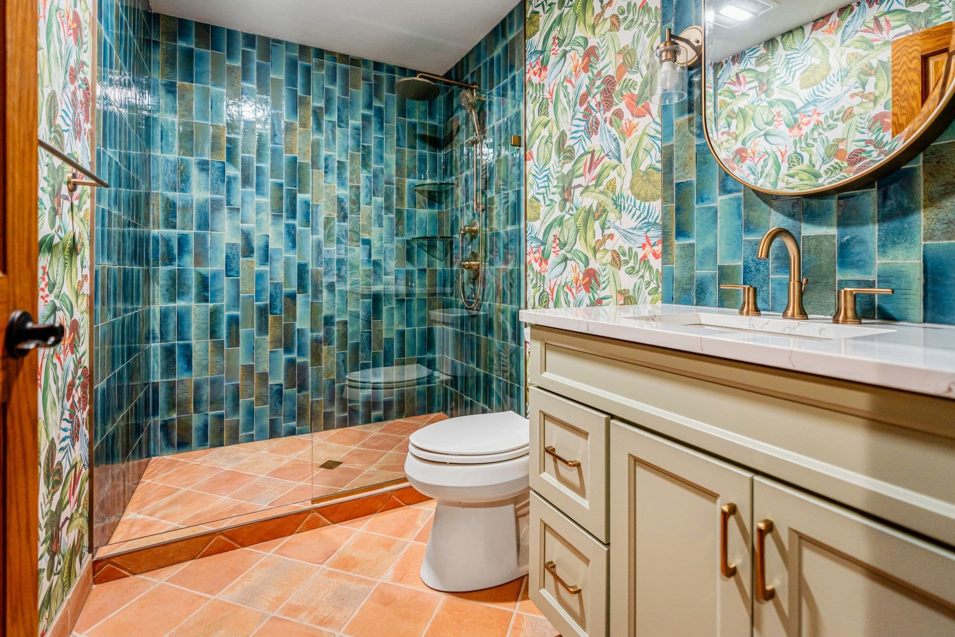 A blue mosaic style tiled walk-in shower and new white and gold vanity.