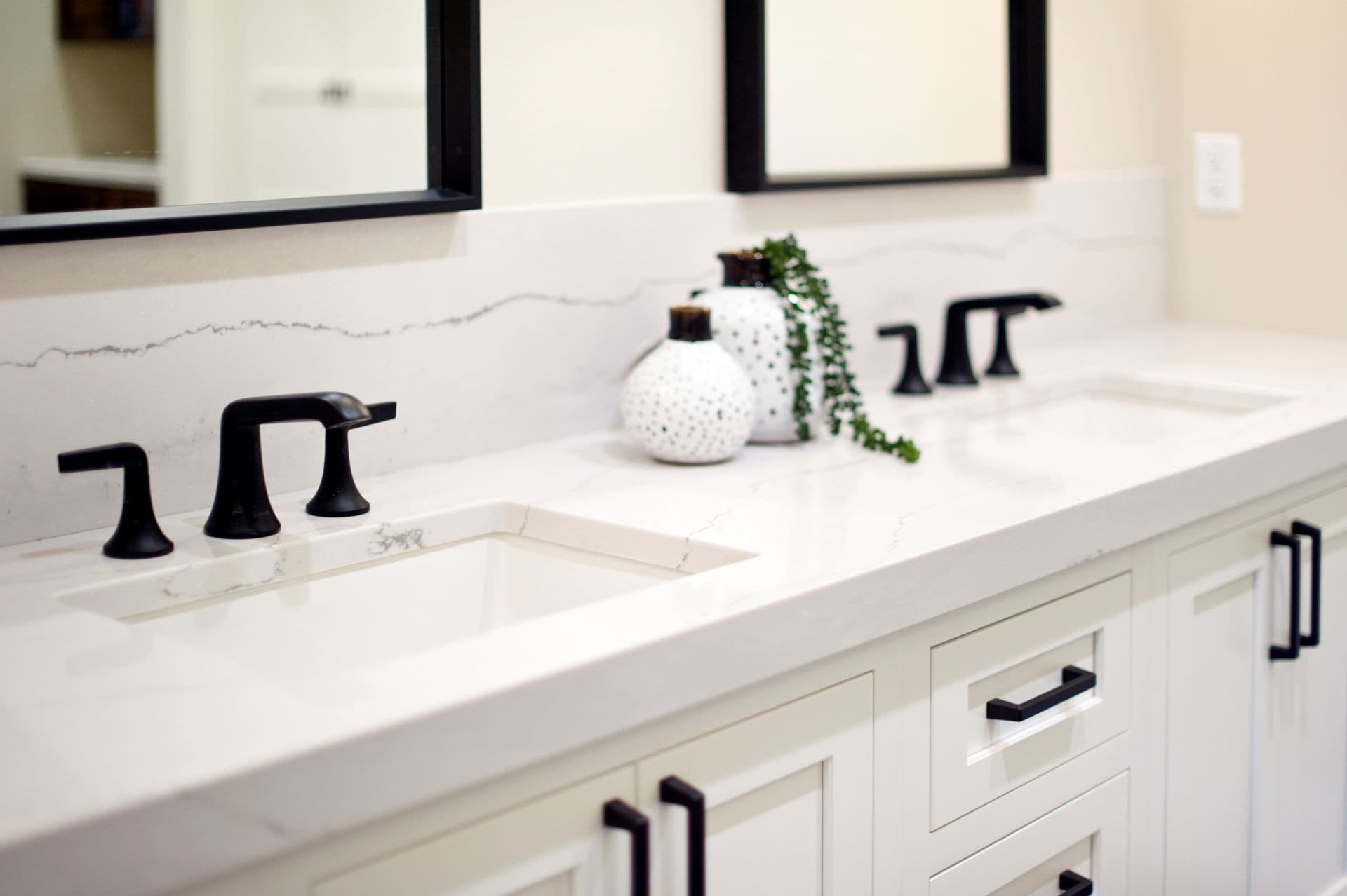 A double vanity with white countertop and cabinets and matte black fixtures.