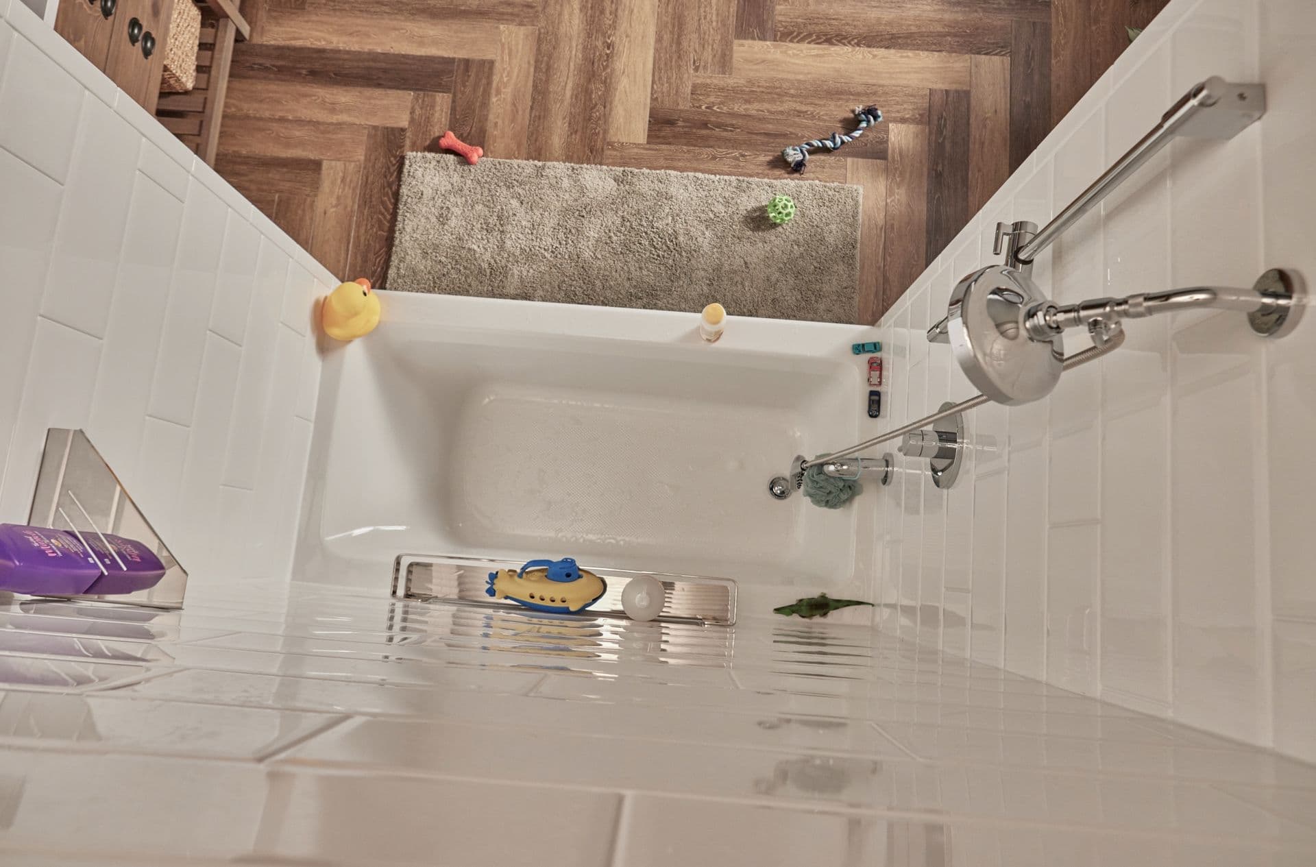 A top down view of a white combination shower bathtub with subway tile walls.